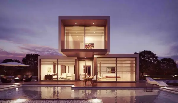 Moderne Villa mit Pool und Terrasse, ideal für den Hausbau planen. Beleuchtete Innenräume und ein schöner Abendhimmel.