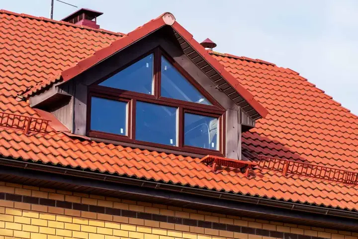 Ein Dachfenster mit dreieckigem Oberlicht und roten Ziegeln. Informieren Sie sich, was kostet eine gaube für Ihr Haus.
